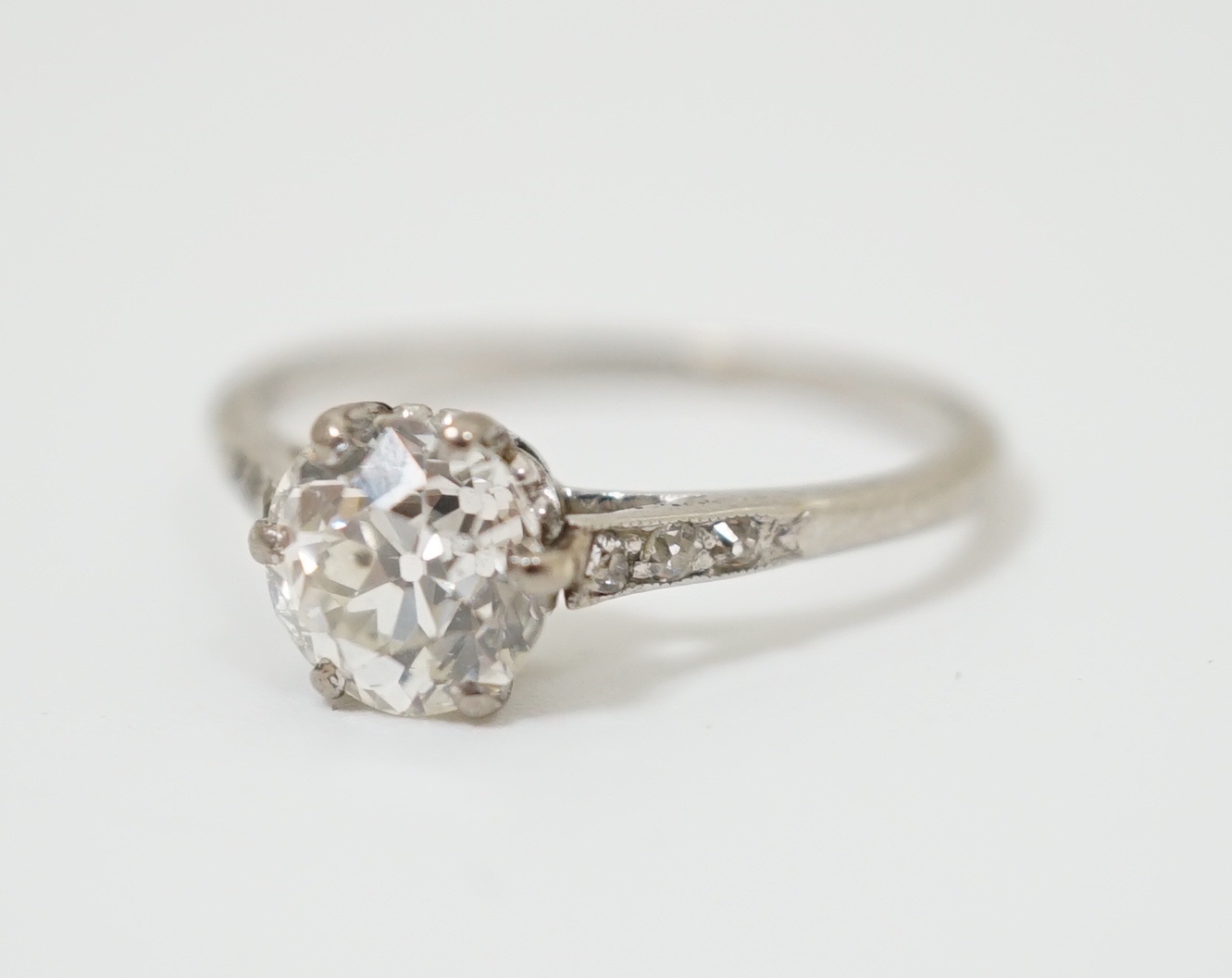 A platinum and single stone diamond ring, with diamond chip set shoulders